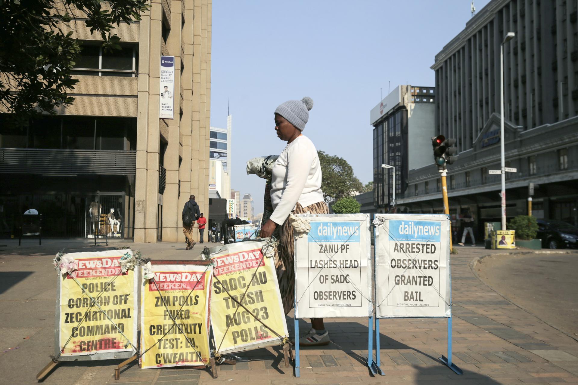 A person walks past posters depicting newspaper front pages near the Zimbabwe Electoral Commission (ZEC) offices in Harare, Zimbabwe, 26 August 2023. EFE-EPA/AARON UFUMELI
