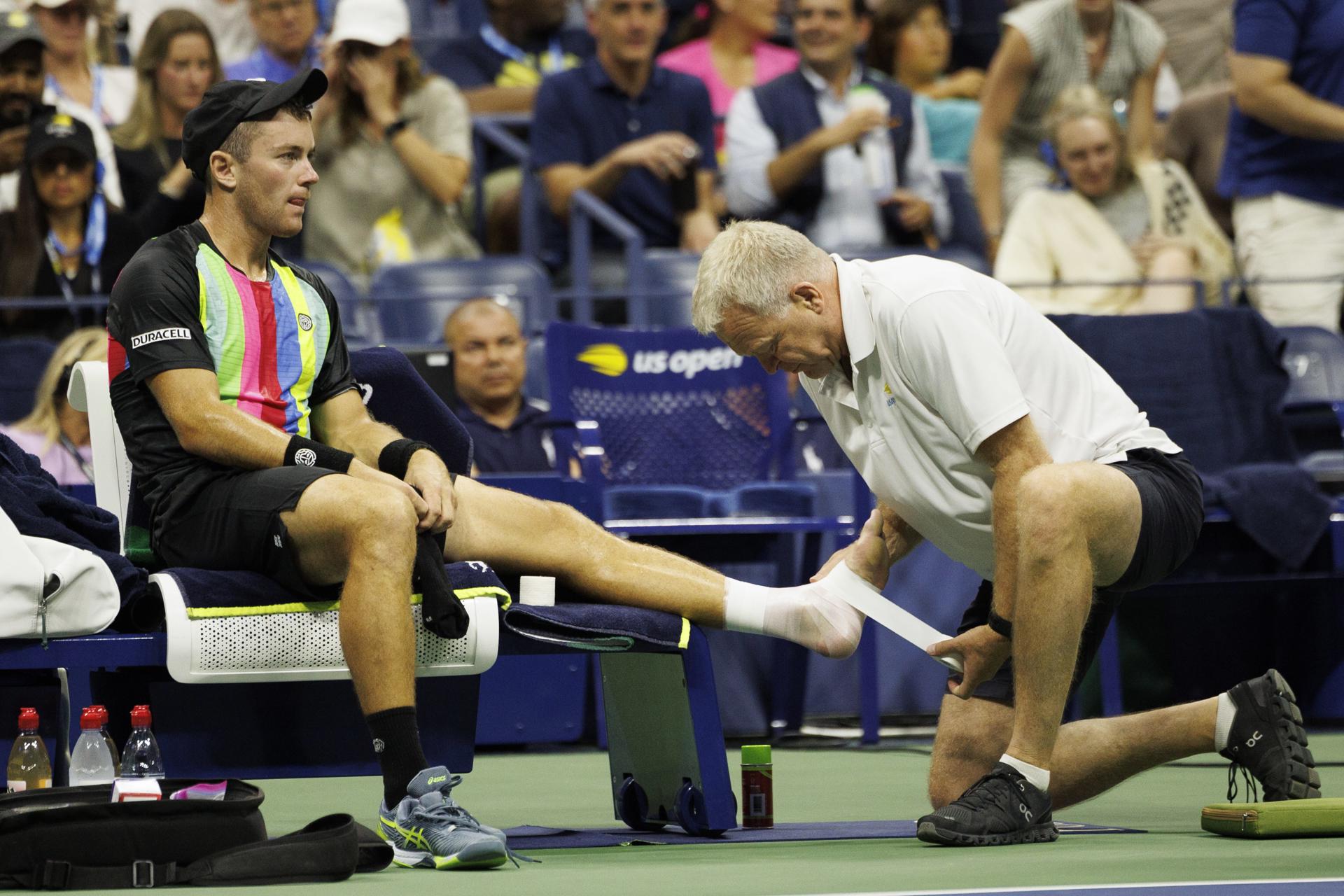 Dominik Koepfer of Germany (L) has his foot wrapped by a medical attendent after taking an injury time out during his first round match against Carlos Alcaraz of Spain at the US Open Tennis Championships at the USTA National Tennis Center in Flushing Meadows, New York, USA, 29 August 2023. EFE-EPA/CJ GUNTHER
