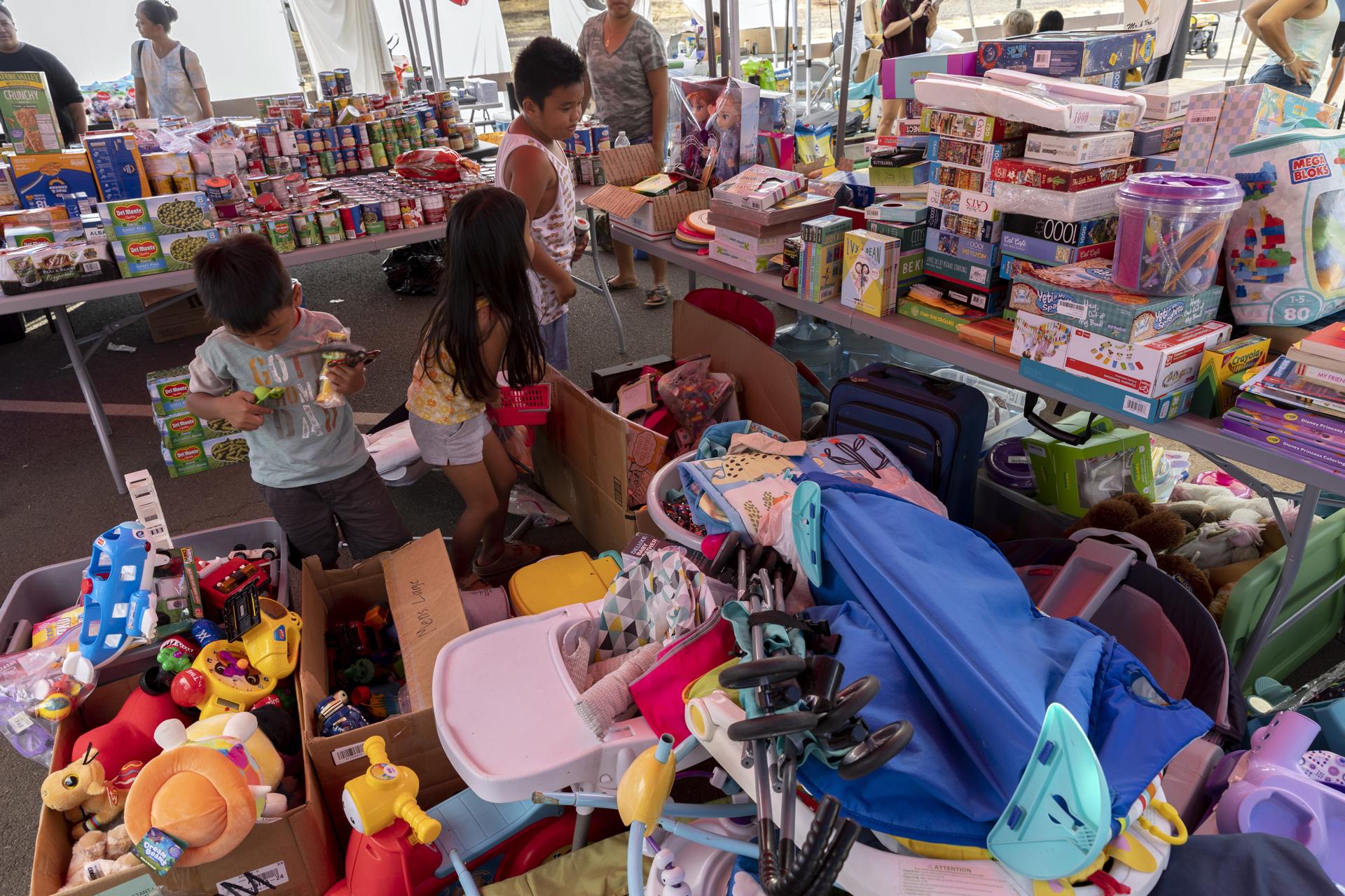Daily (C), Liam (R) and their brother check boxes of donated toys at a distribution location in a neighborhood of Lahaina, Hawaii, USA, 13 August 2023. EFE-EPA/ETIENNE LAURENT
