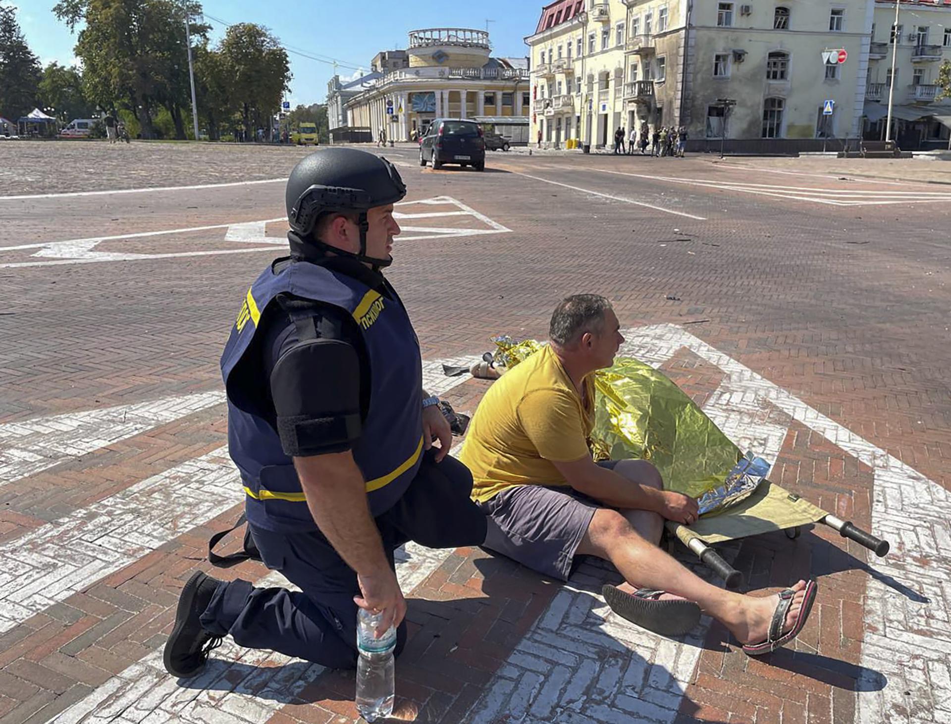 A handout photo made available by the State Emergency Service of Ukraine shows a man sitting next to the covered body of a victim at the area where a missile hit the Drama Theatre downtown of Chernihiv, Ukraine, 19 August 2023. EFE/EPA/STATE EMERGENCY SERVICE OF UKRAINE HANDOUT HANDOUT EDITORIAL USE ONLY/NO SALES
