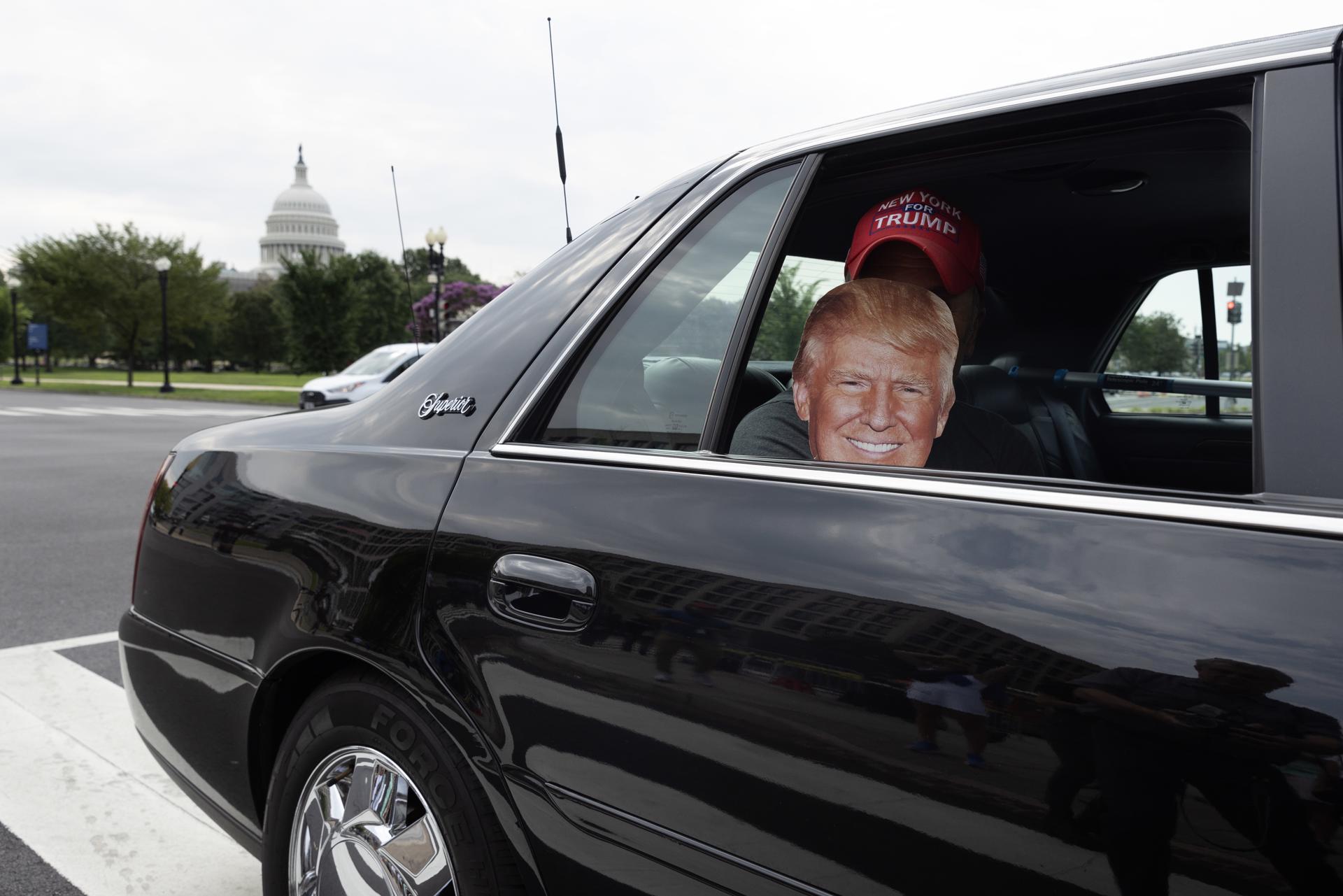 A supporter of Donald Trump wearing a mask with the former president's likeness looks out from the back seat of a car near the US federal courthouse in Washington on 3 August 2023 ahead of Trump's arraignment. EFE/EPA/MICHAEL REYNOLDS
