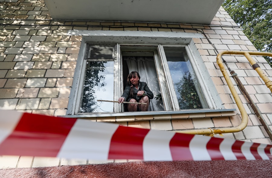 Una mujer retira fragmentos de una ventana destrozada por una onda expansiva en su apartamento cerca de un edificio dañado en Moscú