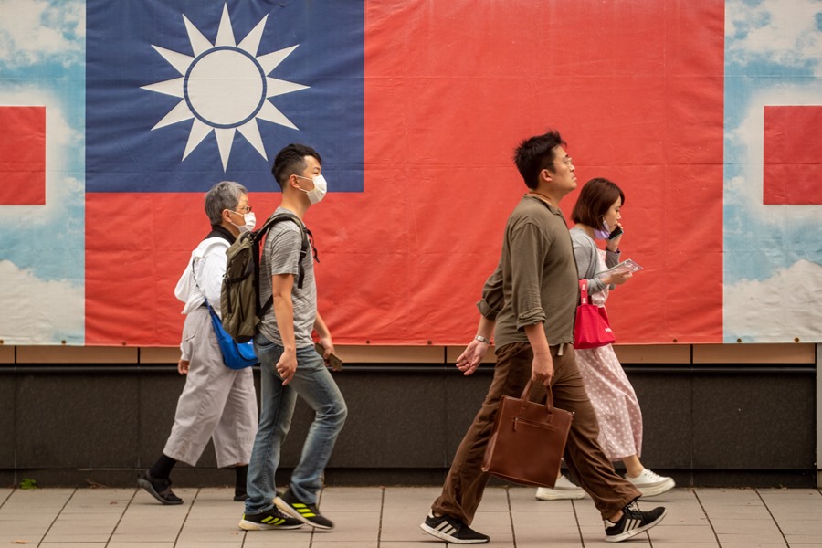 Un grupo de personas pasa ante la bandera de Taiwán