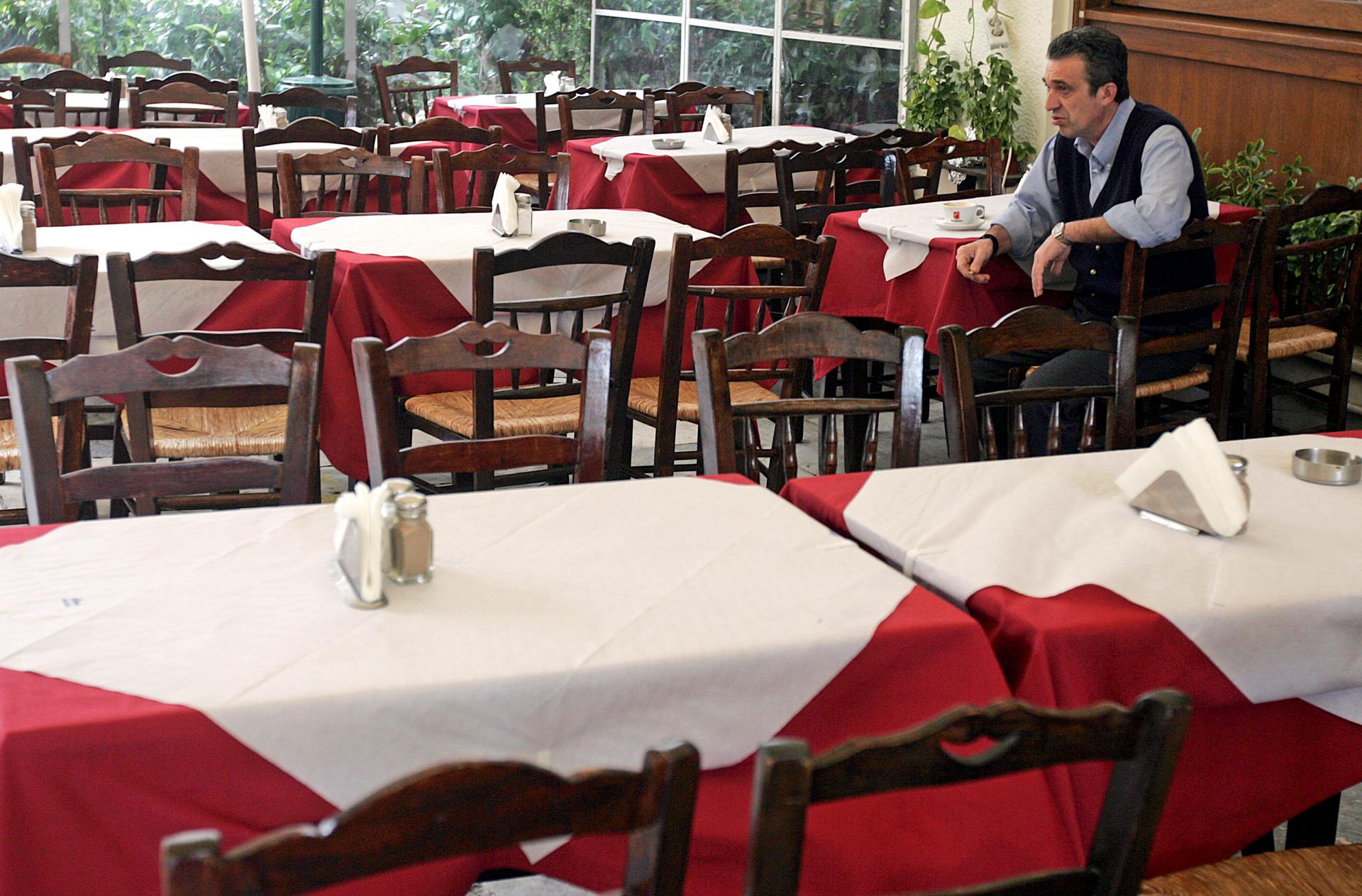 Un camarero que espera la llegada de clientes en un restaurante en Atenas, Grecia.