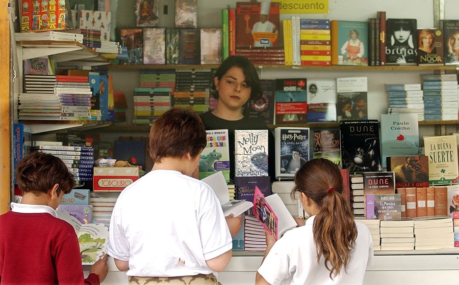 Unos niños hojean unos libros en el expositor de un librería