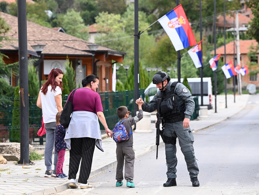 
Un niño saluda a un oficial de policía armado de Kosovo que patrulla la aldea de Banjska, Kosovo
