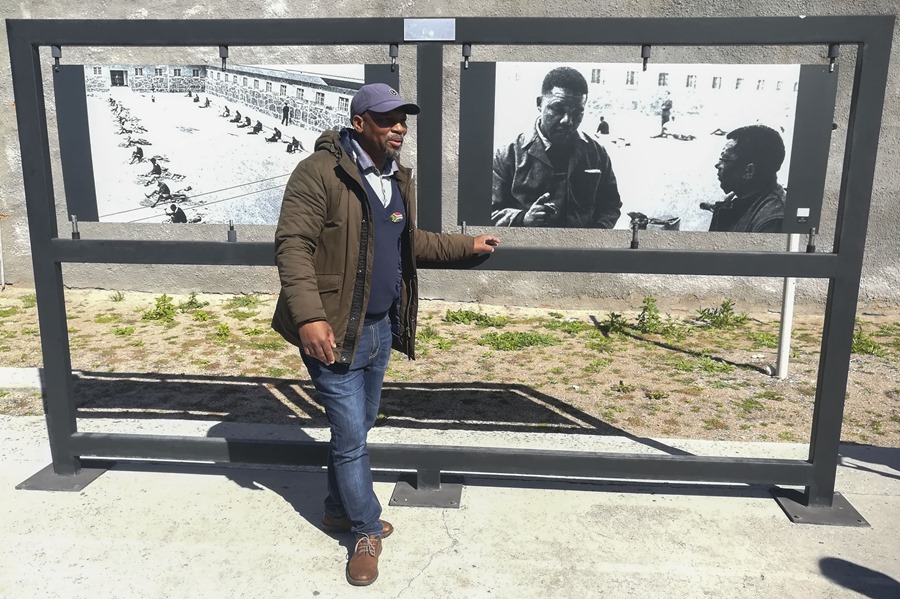 El exrecluso Derick Basson muestra dos grandes fotografías, incluida una en la que Nelson Madela charla con otro preso, en el patio de la Sección B de la Prisión de Máxima Seguridad de la isla de Robben (Sudáfrica).