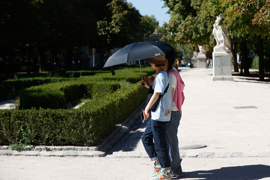Varios turistas se protegen del sol en Madrid.