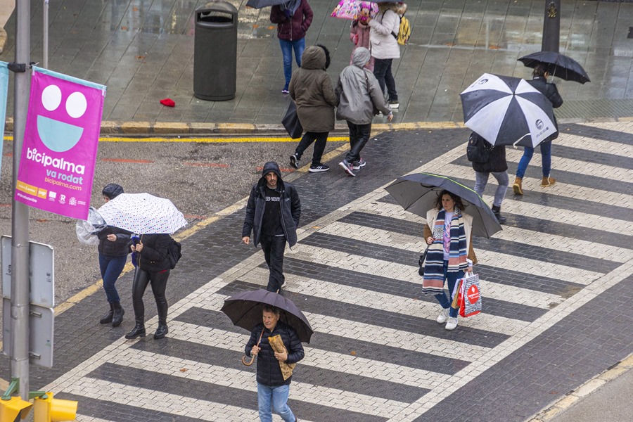 Peatones se protegen con paraguas de la lluvia en Palma