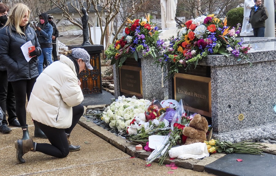 
Una mujer se arrodilla para orar ante la tumba de Lisa Marie Presley en Graceland