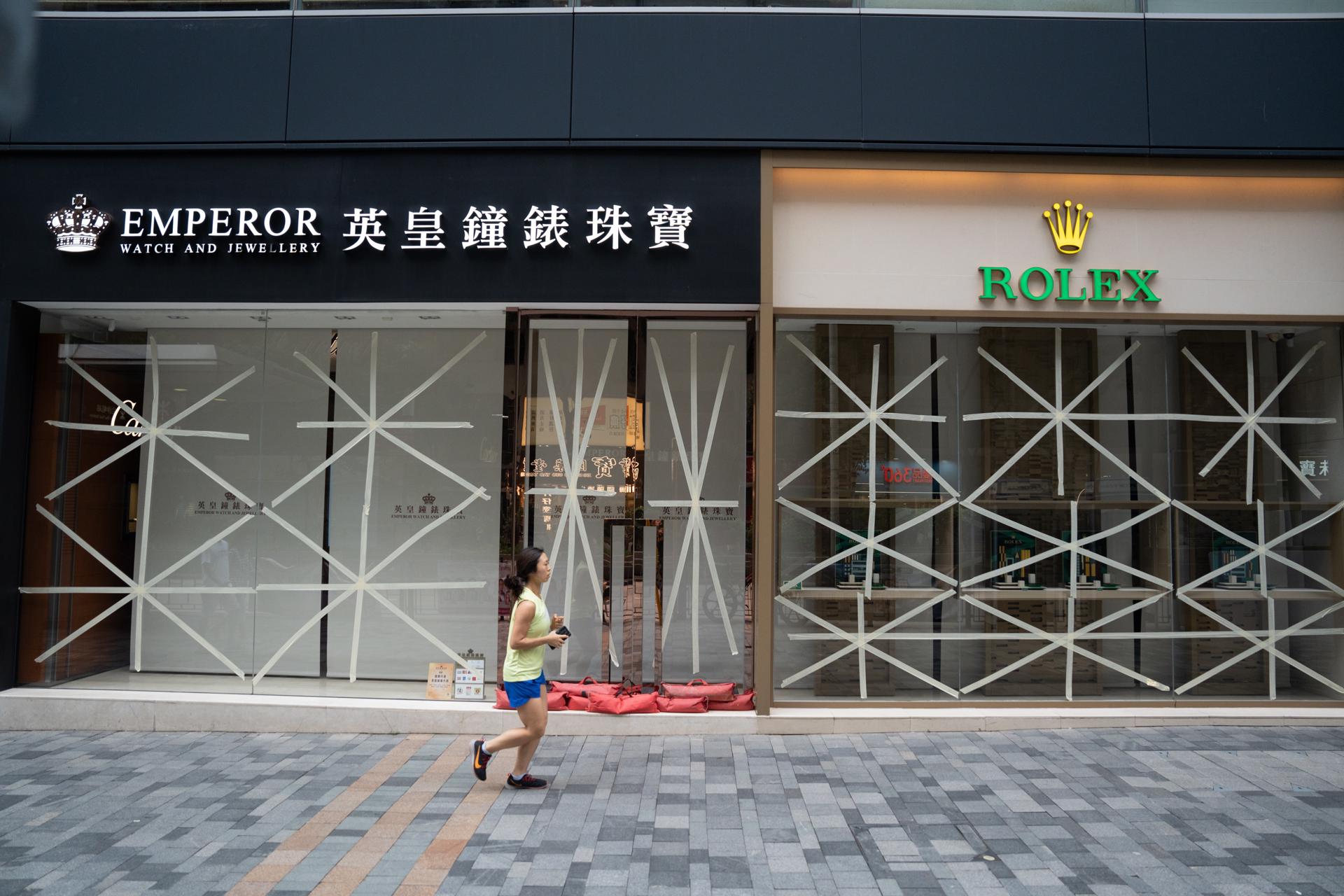 A woman jogs past shops with their windows taped with X signs as a precautionary measure against damage during Typhoon Saola in Tsim Sea Tsui, Hong Kong, China, 01 September 2023. EFE-EPA/Bertha Wang
