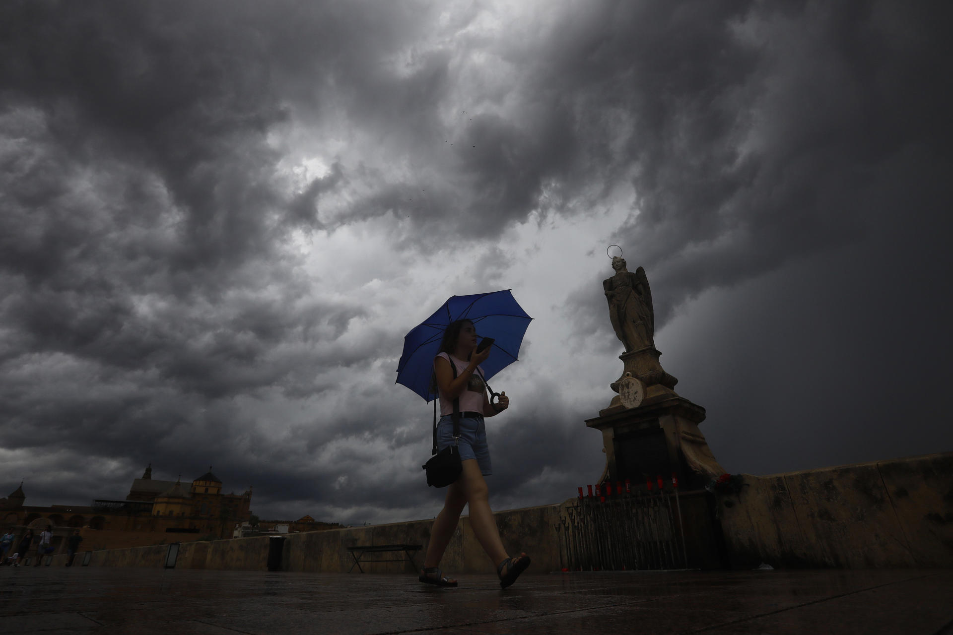 Una mujer se protege de la lluvias en el puente romano de Córdoba. EFE/Salas
