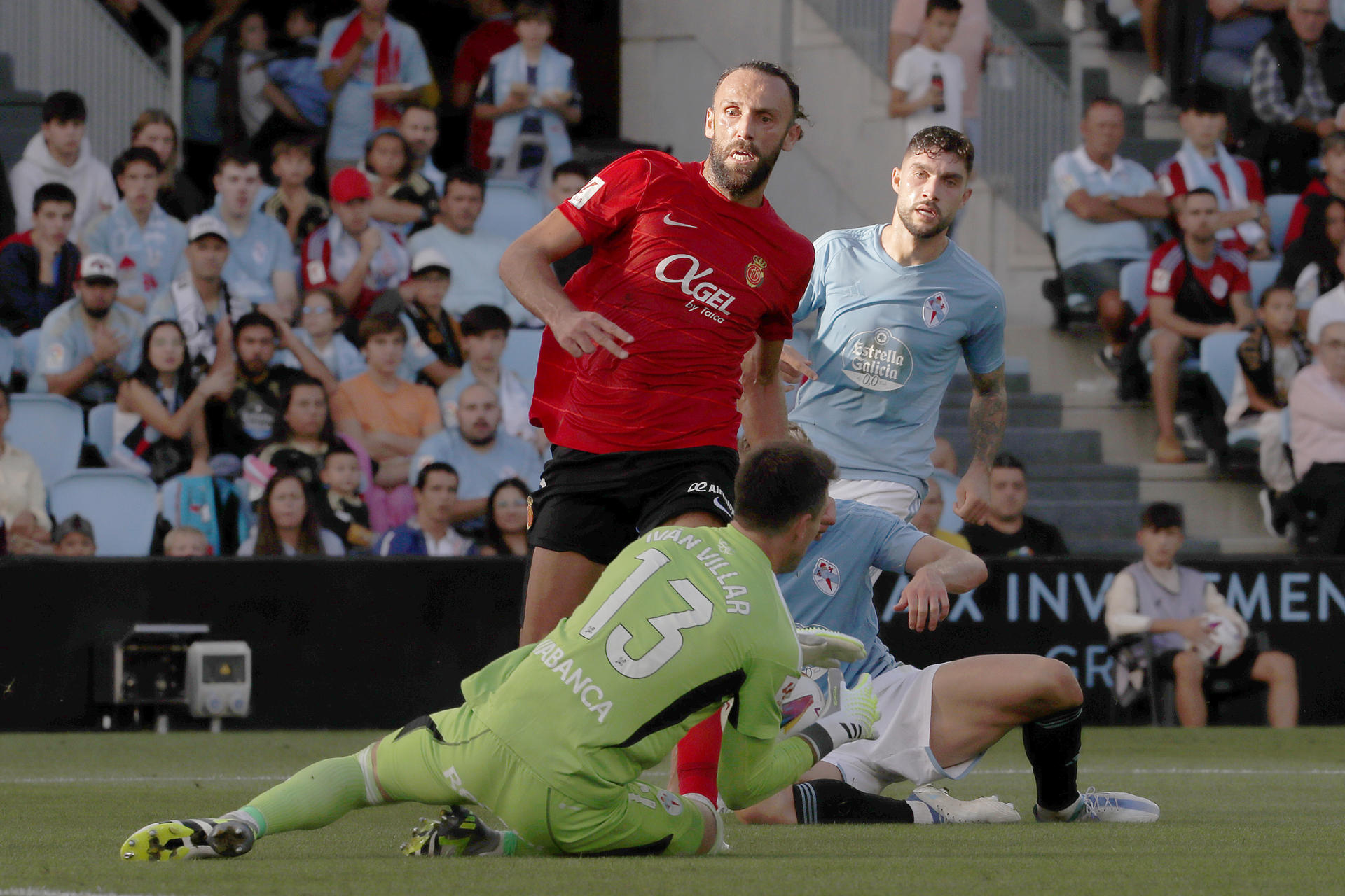 El guardameta del Celta, Iván Villar (i), detiene el balón ante el delantero albanés del Mallorca, Vedat Muriqi, durante el encuentro correspondiente a la quinta jornada de primera división que han disputado en el estadio de Balaidos, en Vigo. EFE / Salvador Sas.