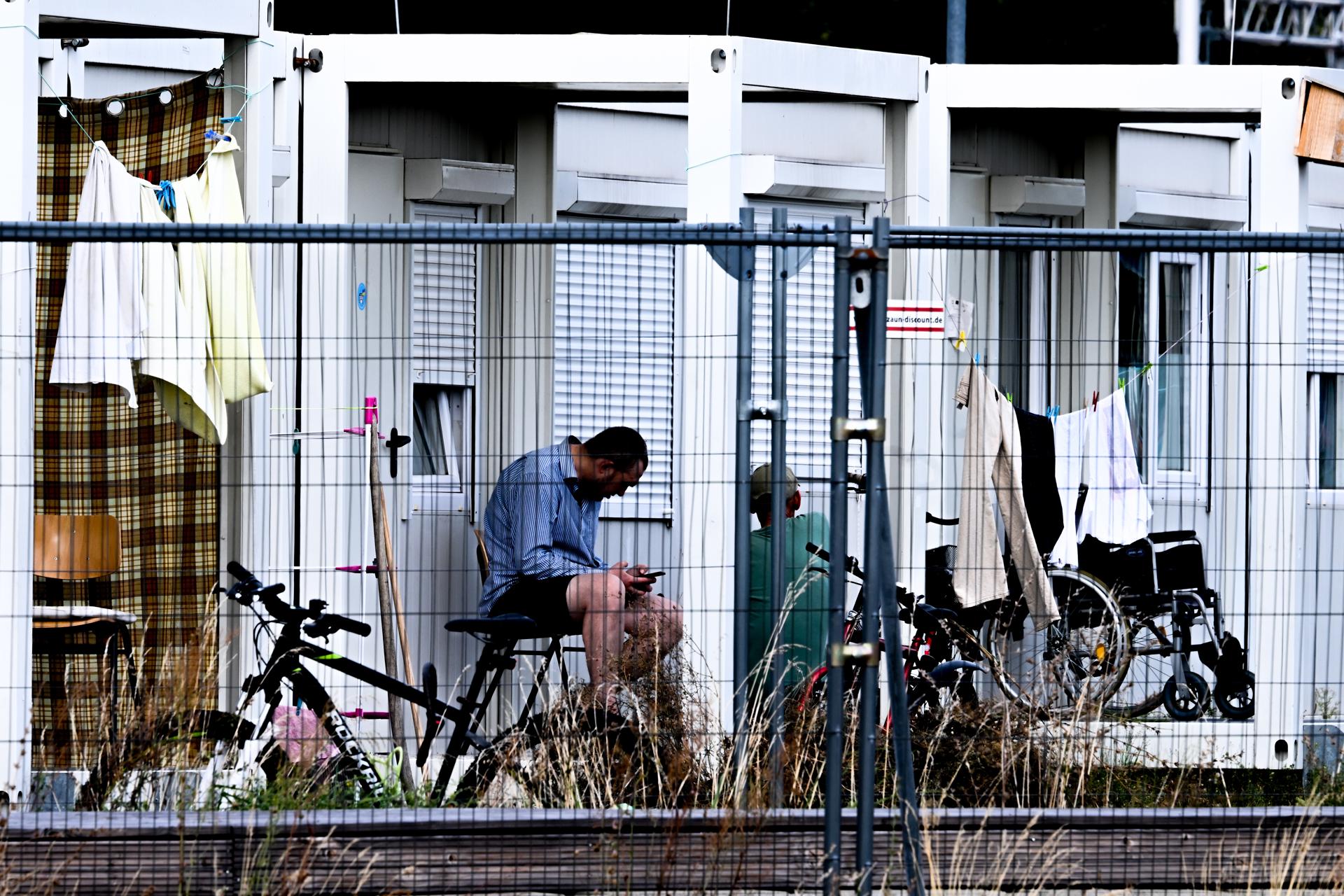 Berlin (Germany), 19/09/2023.- A refugee sits in front of containers used as houses for refugees at former Berlin Tempelhof airport in Berlin, Germany, 19 September 2023. (Alemania, Ucrania) EFE/EPA/Filip Singer
