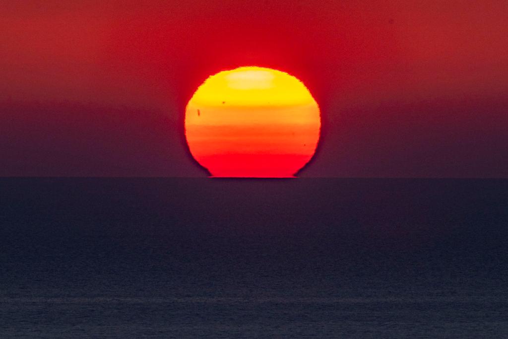 El sol se pone sobre la línea del horizonte en el mar. 
