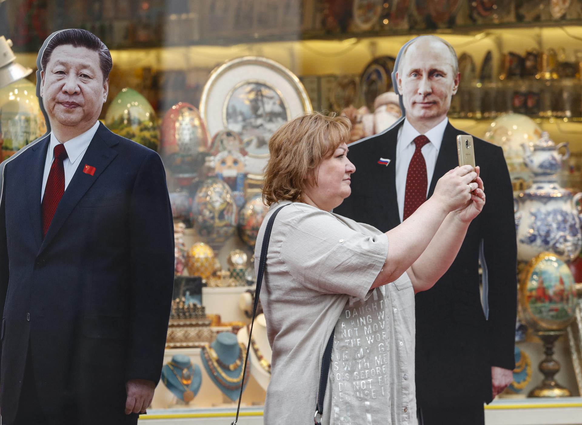 A woman takes pictures with a cardboard cut-outs of Russian President Vladimir Putin and China's President Xi Jinping (L) in downtown of Moscow, Russia, 28 June 2023. EFE-EPA FILE/MAXIM SHIPENKOV