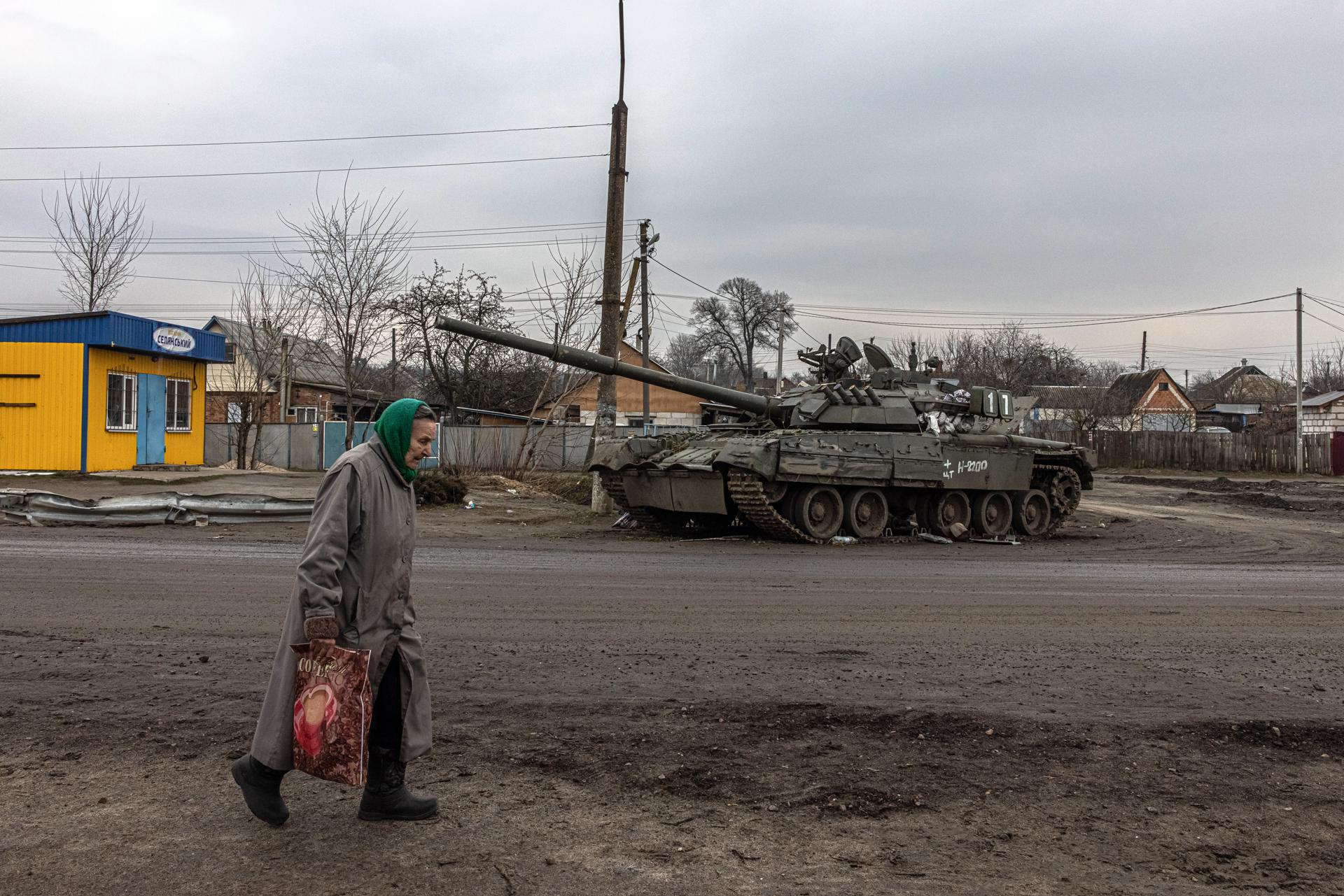 An elderly woman walks past a damaged Russian tank in recaptured by the Ukrainian army Trostyanets town, in Sumy region, Ukraine, 30 March 2022. EFE-EPA FILE/ROMAN PILIPEY

