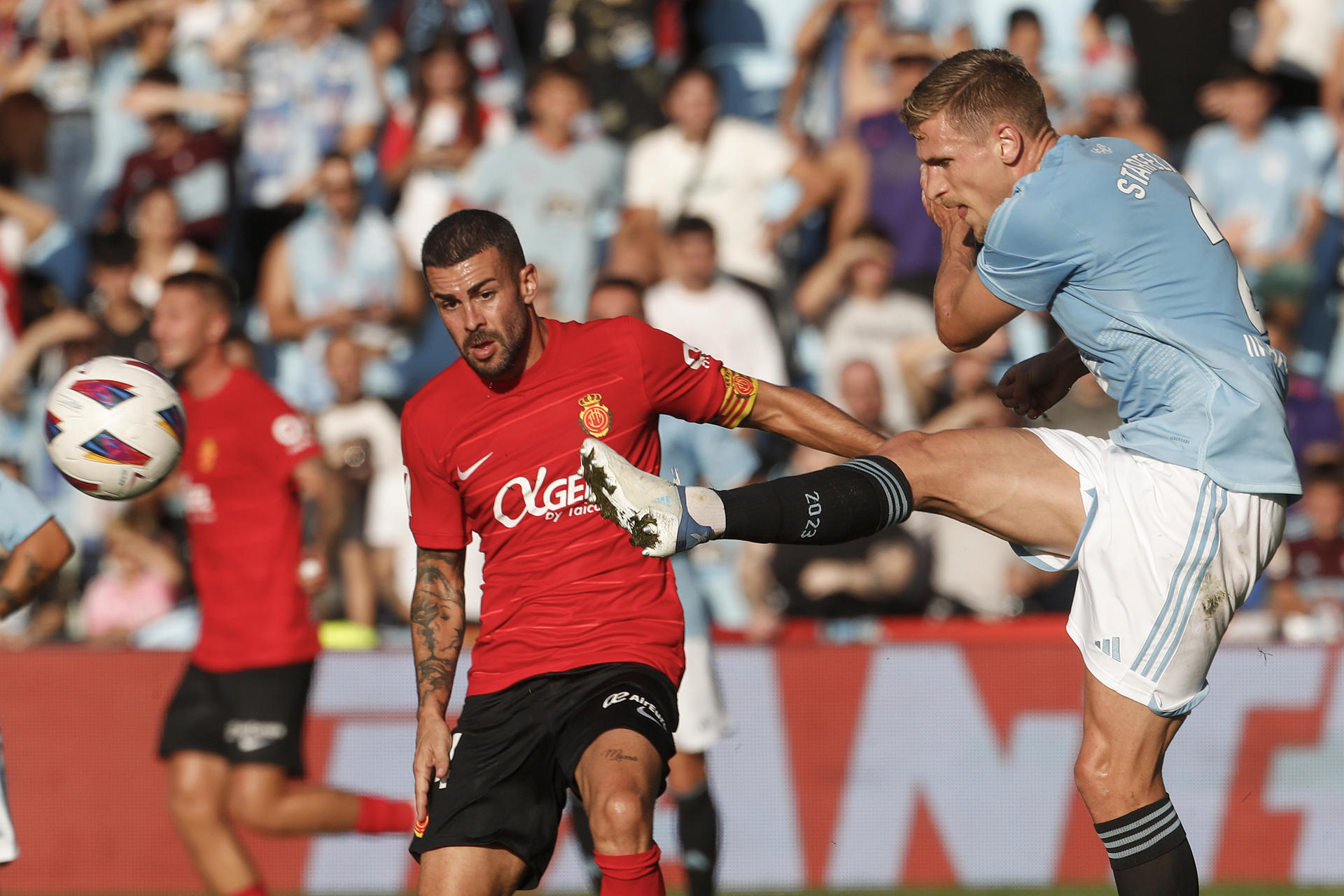 El delantero noruego del Celta, Jorgen Strand Larsen (d), golpea el balón ante el centrocampista del Mallorca, Dani, durante el encuentro correspondiente a la quinta jornada de primera división que han disputado en el estadio de Balaidos, en Vigo. EFE / Salvador Sas.
