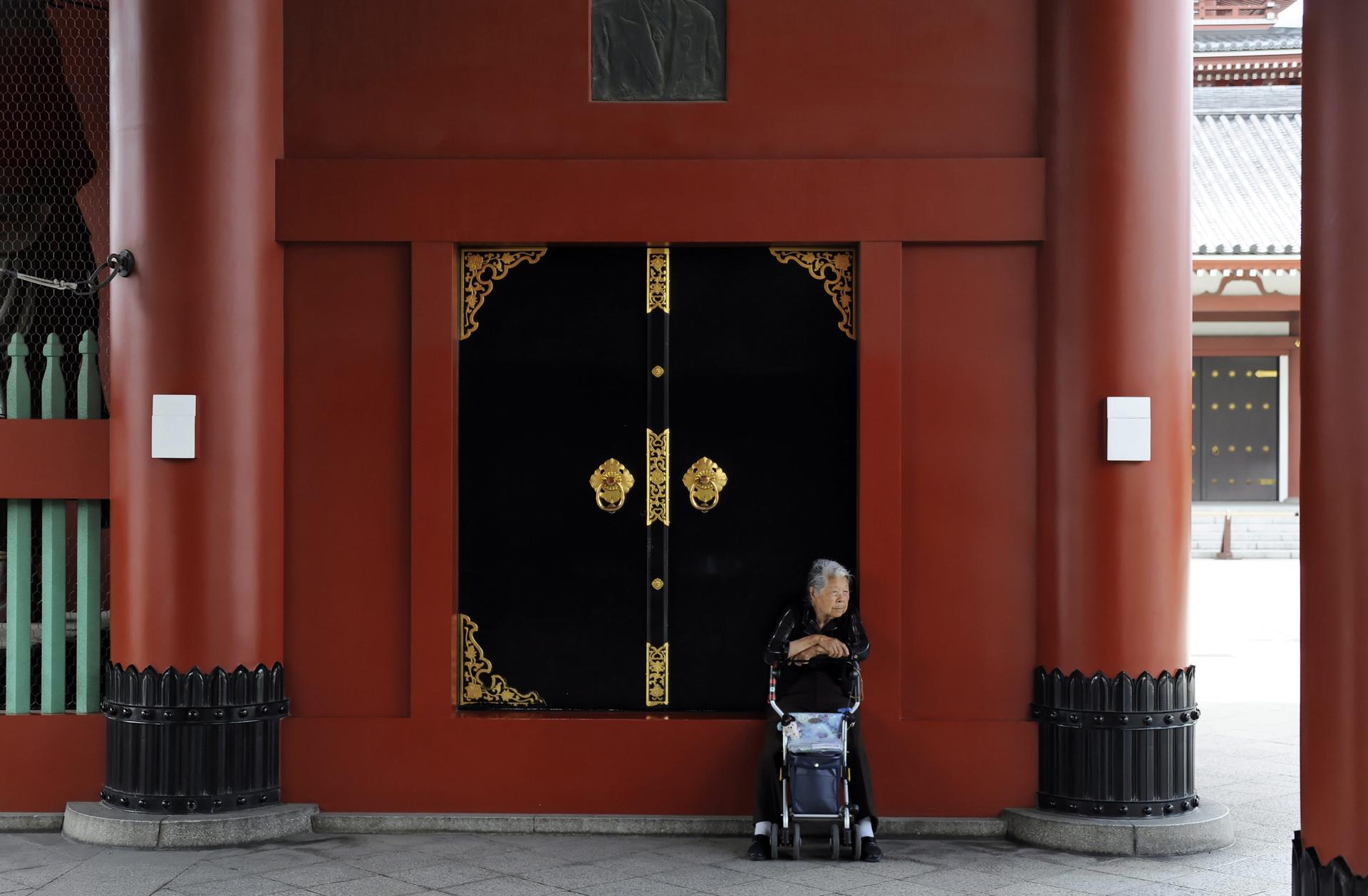 An elderly woman takes a break in the shadow of a large gate at the Sensoji temple in Tokyo's Asakusa district, Japan, 24 June 2011.EPA-EFE FILE/FRANCK ROBICHON