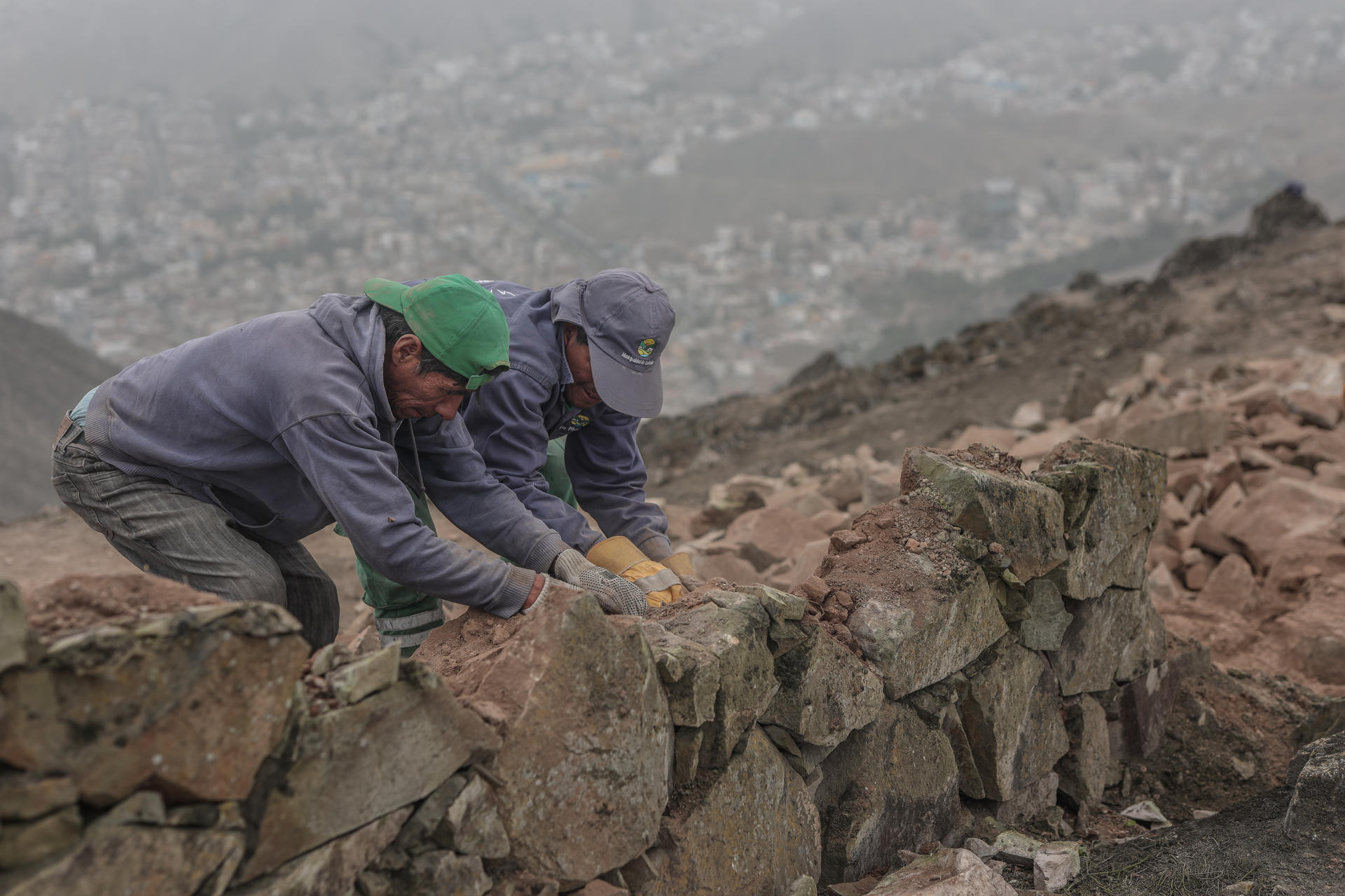 Operarios trabajan en el desmonte de un muro que divide los distritos de La Molina y Villa del Triunfo hoy, en Lima (Perú). EFE/Aldair Mejía