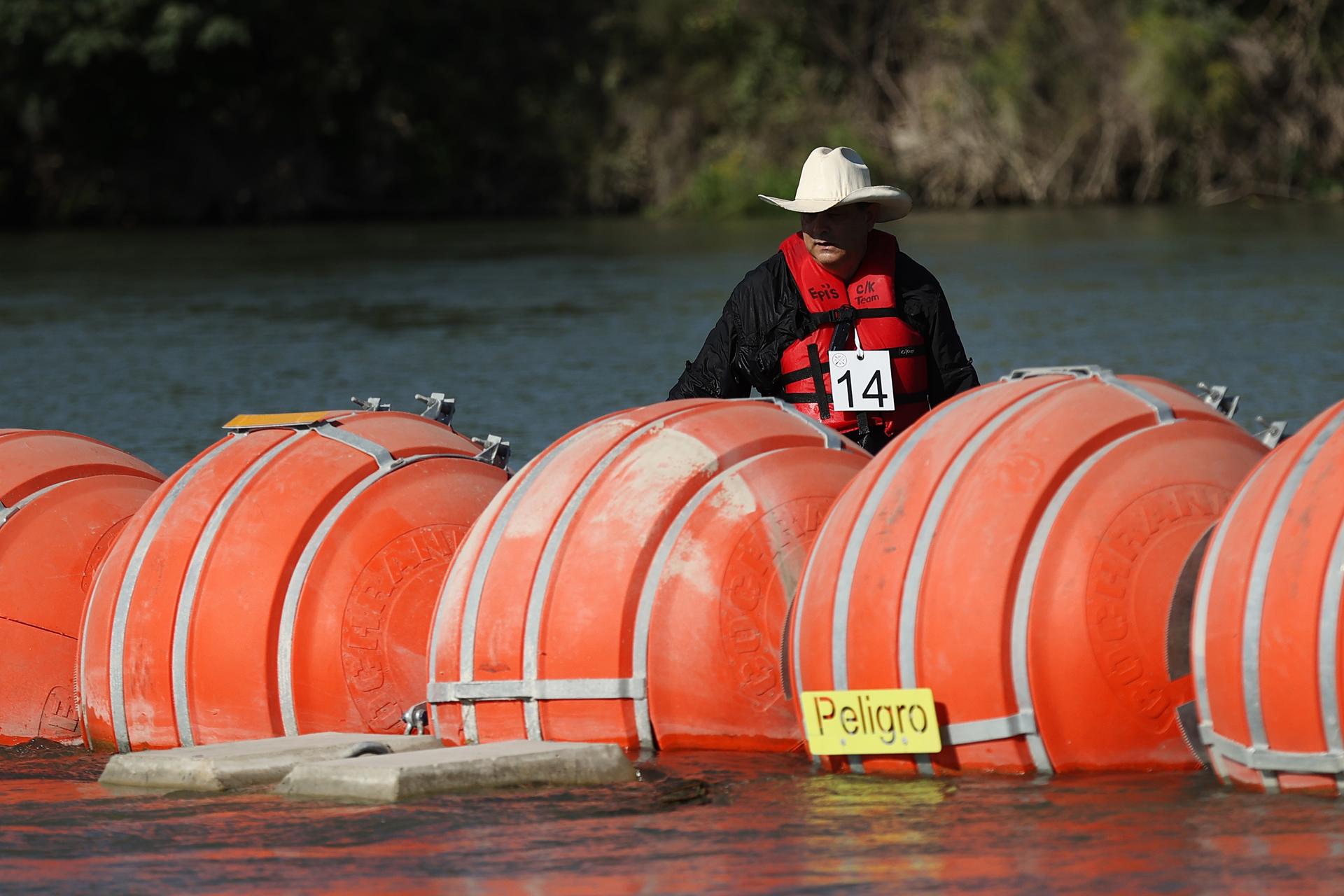 A person inspects the buoys that are placed in the Rio Grande River in Eagle Pass, Texas, USA, 01 August 2023. EFE-EPA FILE/ADAM DAVIS