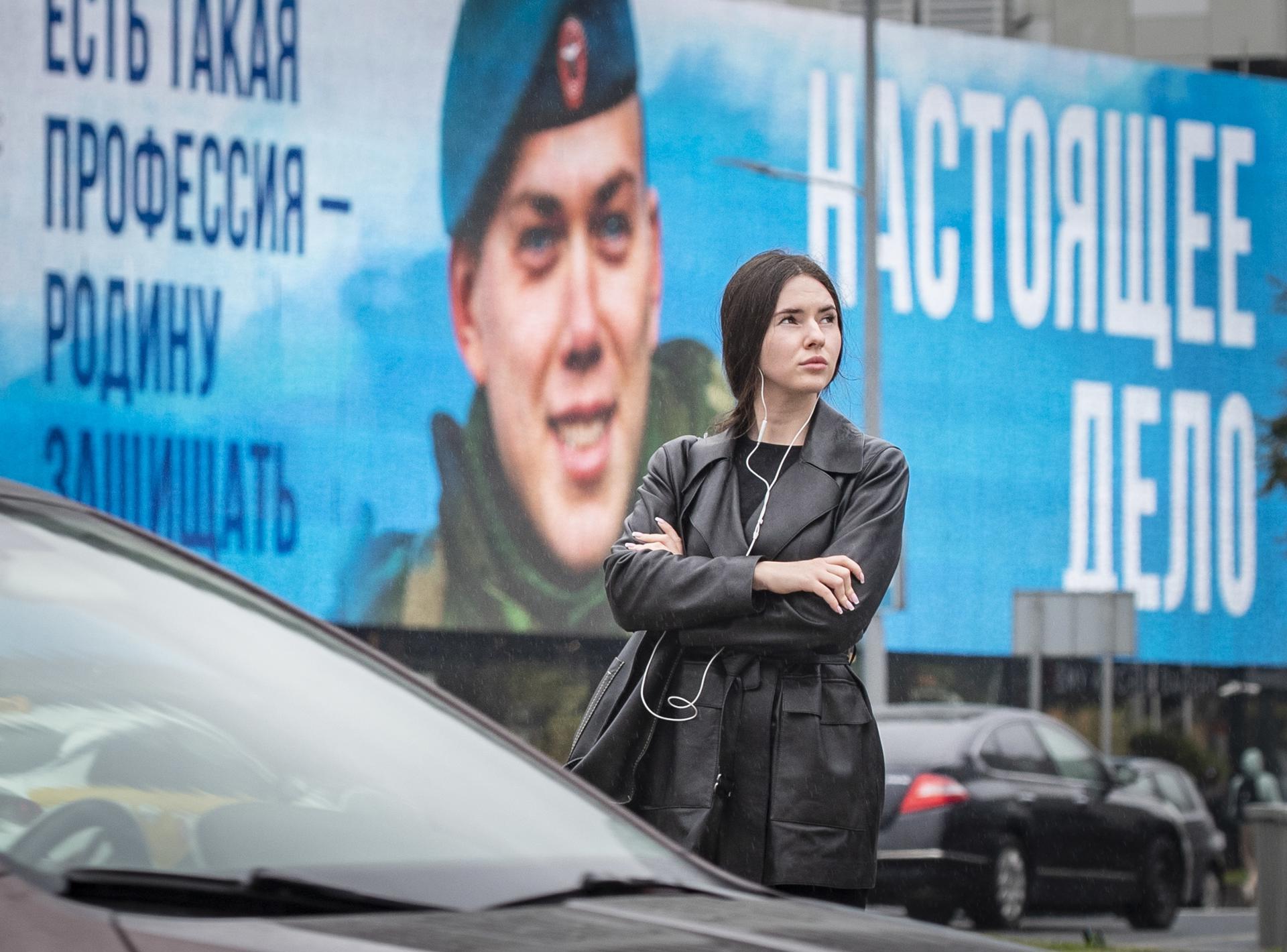 A woman crosses a street past a billboard advertising military conscription reading 'There is such a profession as defending the homeland, in Moscow, Russia, 18 September 2023. EFE-EPA/YURI KOCHETKOV