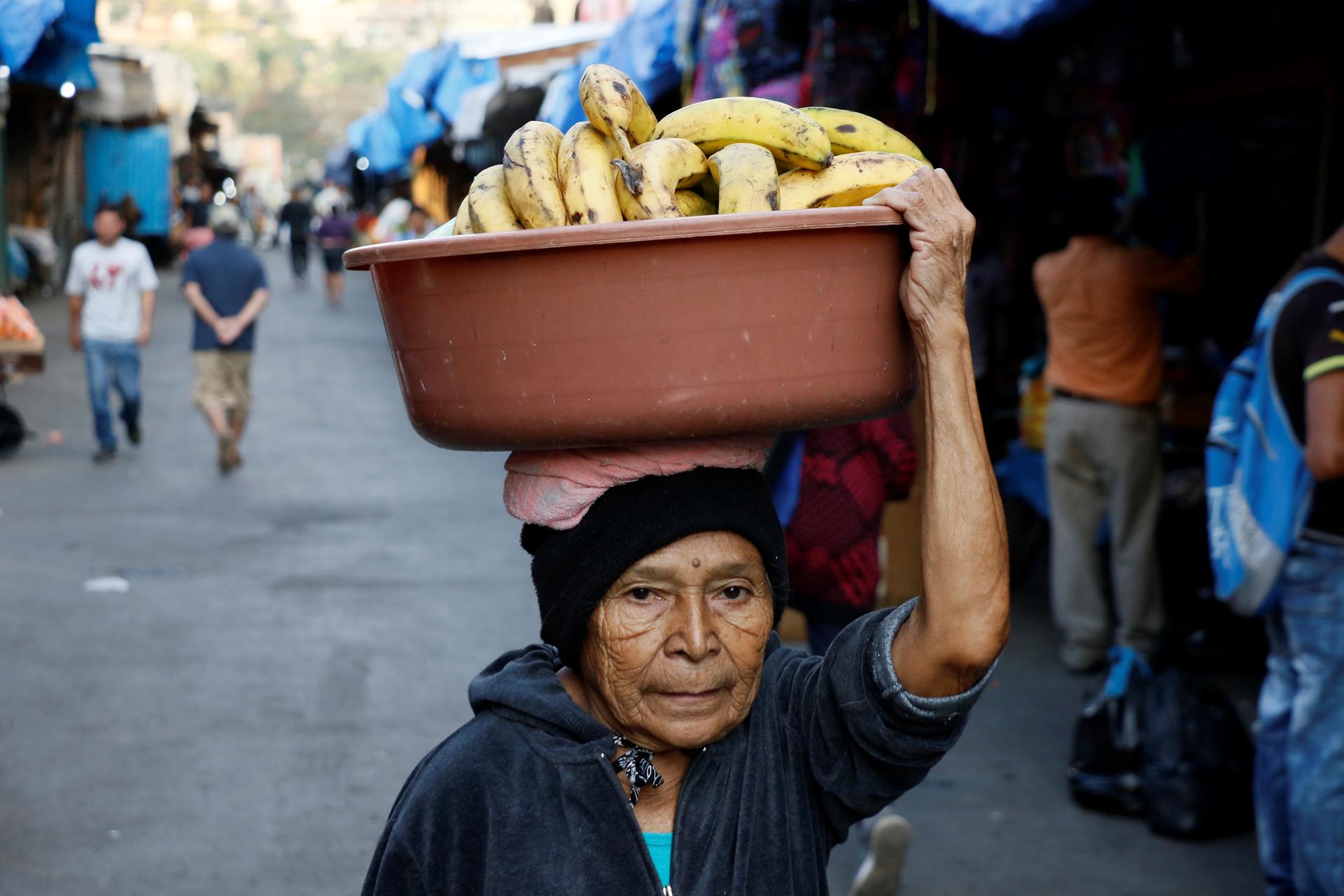 Fotografía de archivo donde aparece una mujer mientras lleva un balde con plátano encima de la cabeza en Tegucigalpa (Honduras). EFE/Humberto Espinoza