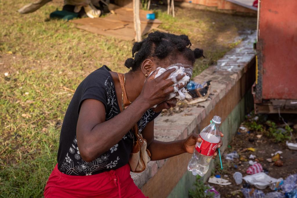 Fotografía de archivo donde aparece una mujer mientras lava su rostro con jabón y una botella con agua en una calle en Puerto Príncipe (Haití). EFE/Johnson Sabin
