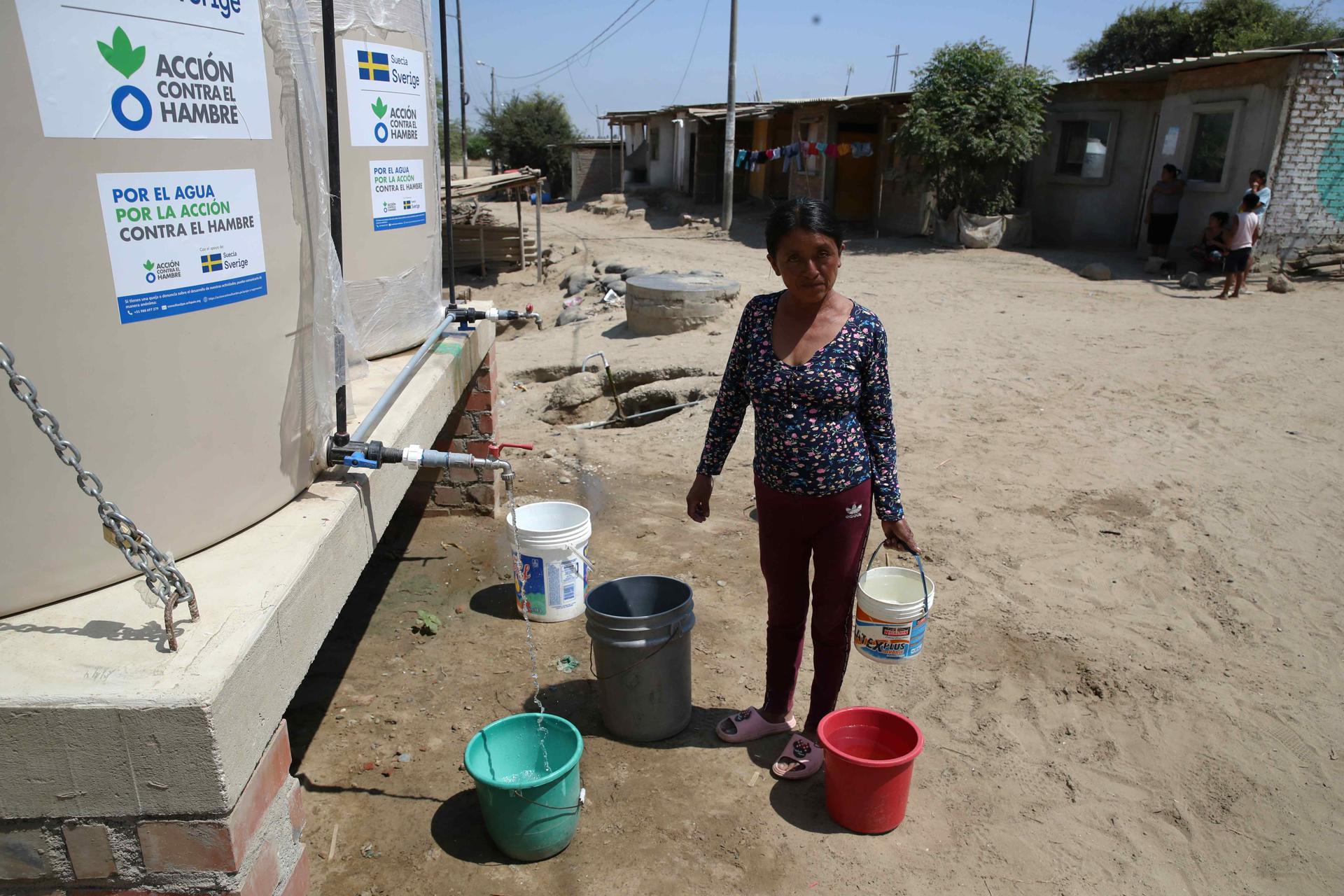 A woman fills buckets with water from the drums installed by Action Against Hunger, in the town of Mocara, department of Piura, Peru, 19 September 2023. EFE/Paolo Aguilar
