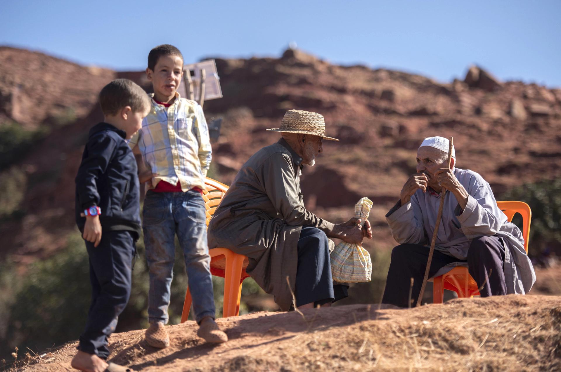 Children stand next to elderly men as support operations and the distribution of waterproof tents and aid continue, in the earthquake-hit village of Tifarouine, Morocco, 23 September 2023. EFE-EPA/STR
