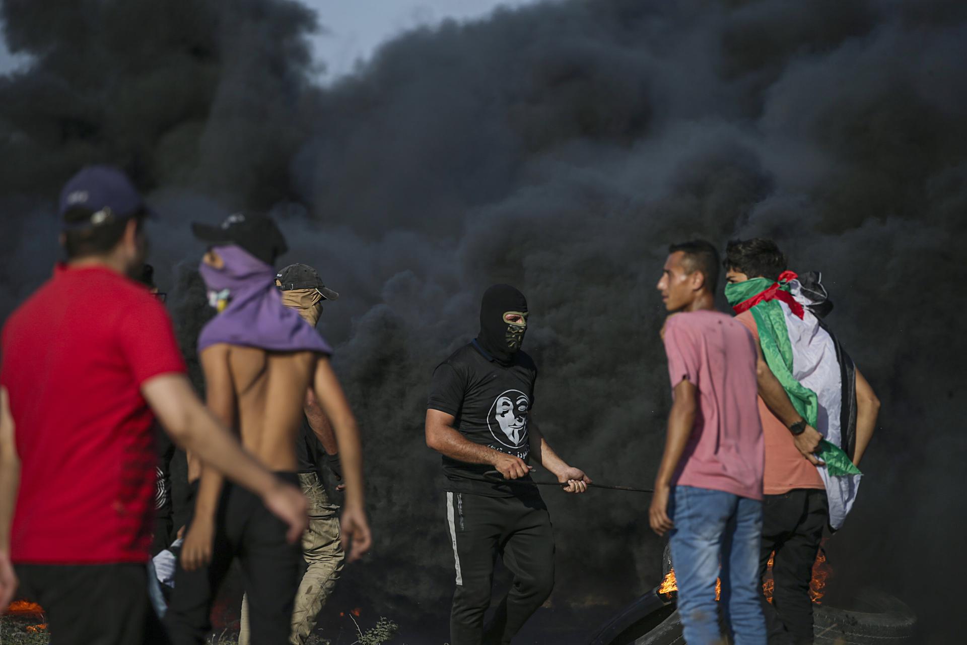 Palestinian protesters stand near black smoke billowing from burning objects during clashes on the eastern border of the Gaza Strip, 22 September 2023. EFE/EPA/MOHAMMED SABER