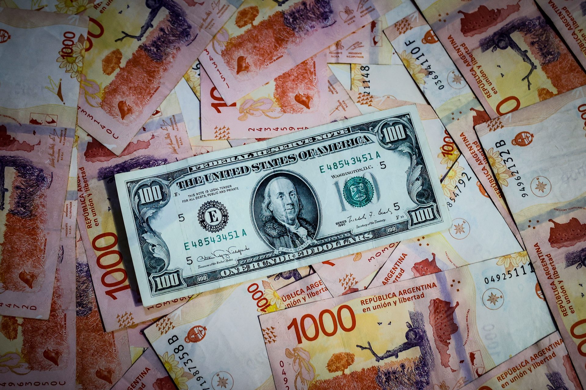 Fotografía de archivo que compara billetes de pesos argentinos con un billete de 100 dolares estadounidenses. EFE/ Juan Ignacio Roncoroni