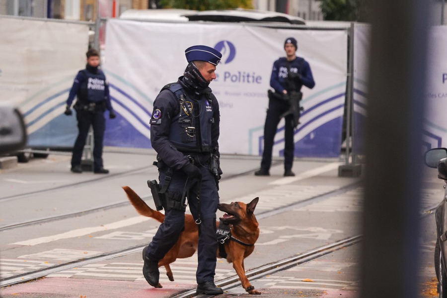 Agentes de policía belgas patrullan con perros la zona en la ha sido localizado el supuesto autor del atentado de anoche en  Bruselas