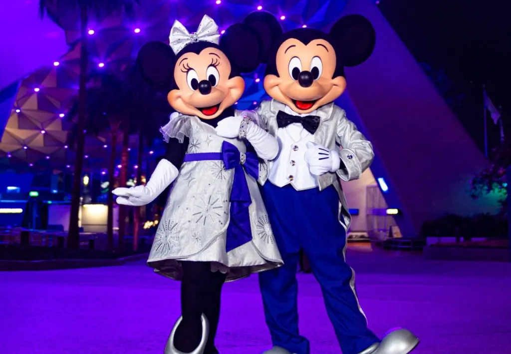 Fotografía cedida por Disney donde aparecen Mickey y Minnie Mouse con sus deslumbrantes trajes platino con ocasión de los 100 años de Disney mientras posan en la entrada del parque temático de EPCOT en Lake Buena Vista, Florida (EE. UU). EFE/Abigail Nilsson/Disney