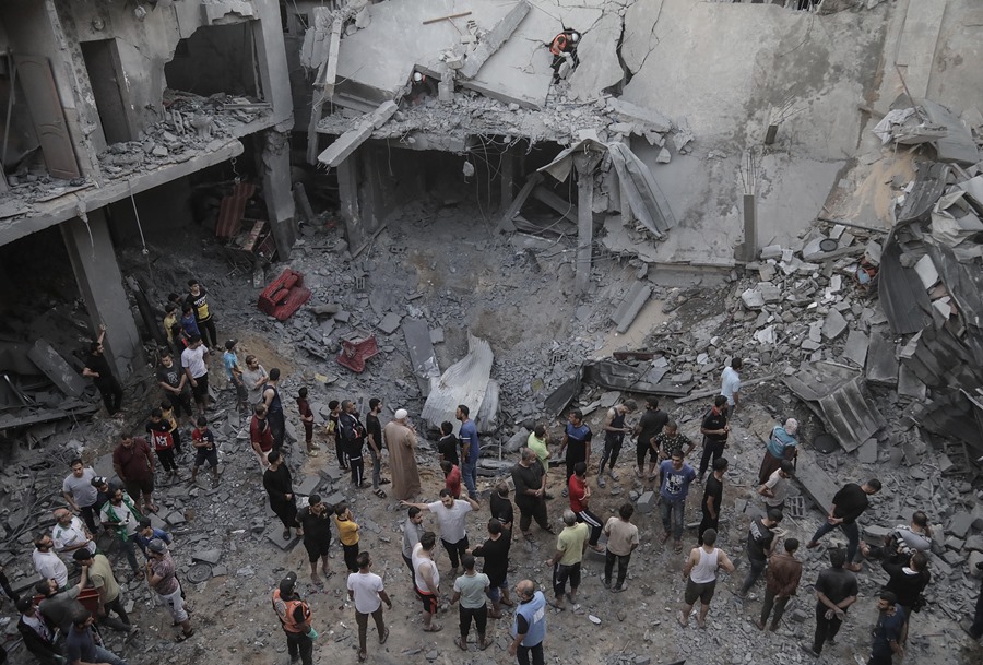 Palestinos buscan cadáveres y supervivientes entre los escombros de un edificio residencial derribado por un ataque aéreo israelí, en el campo de refugiados de Jan Yunis,
