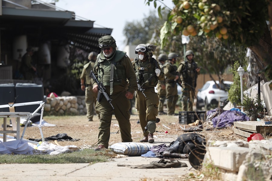 Soldados israelíes caminan junto al cuerpo del militante de Hamas asesinado en el kibutz de Kfar Aza, junto a la frontera con Gaza.