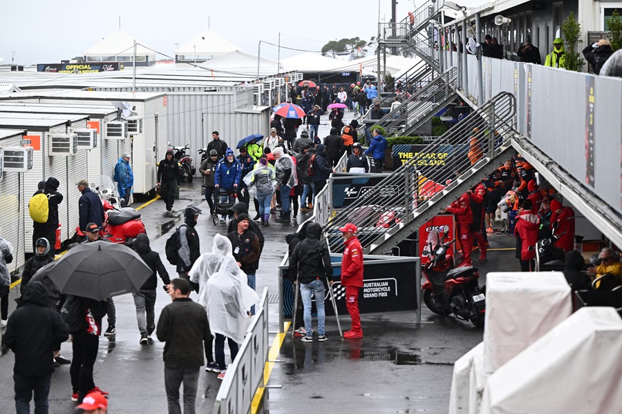 Los corredores y sus equipos se protegen de la lluvia en el paddock del Gran Premio de Motociclismo de Australia, en el circuito de Phillip Island