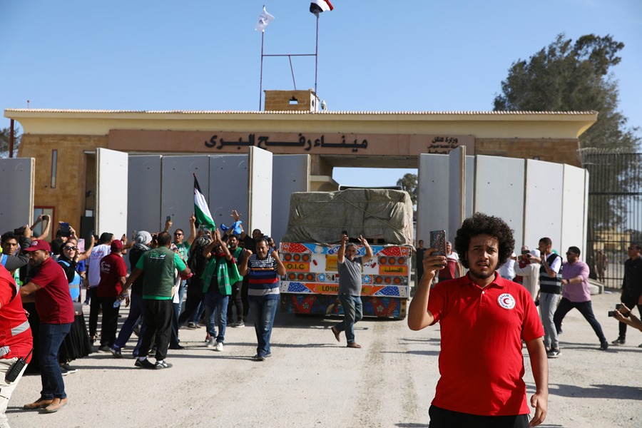 Un camión que transporta ayuda humanitaria para la Franja de Gaza cruza el paso fronterizo de Rafah, desde Egipto, rodeado de voluntarios de varias organizaciones