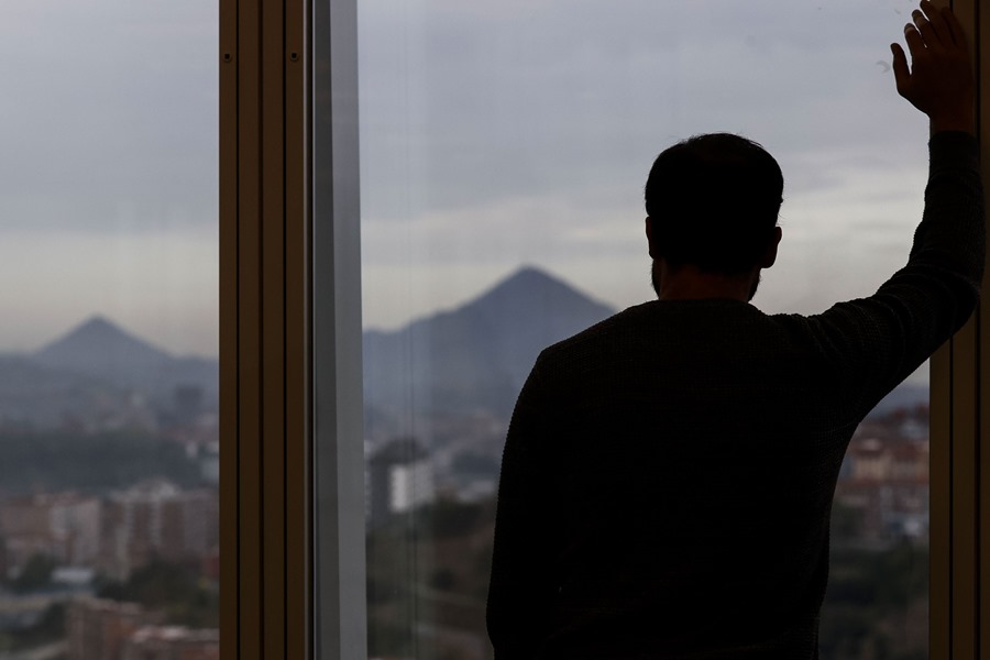Un hombre mira por la ventana de su oficina durante un descanso de su jornada laboral