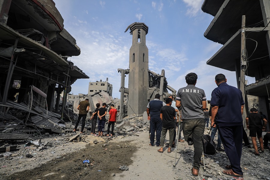 Los palestinos caminan entre los escombros de una zona destruida tras los ataques aéreos israelíes en la ciudad de Gaza.