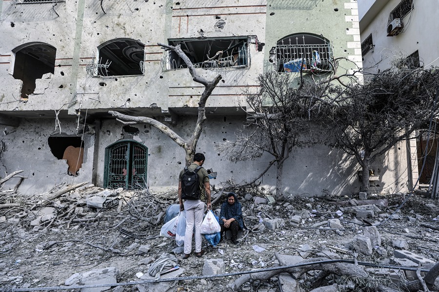 Palestinos en medio de los escombros del barrio Al- Ramal tras un ataque aéreo de Israel.