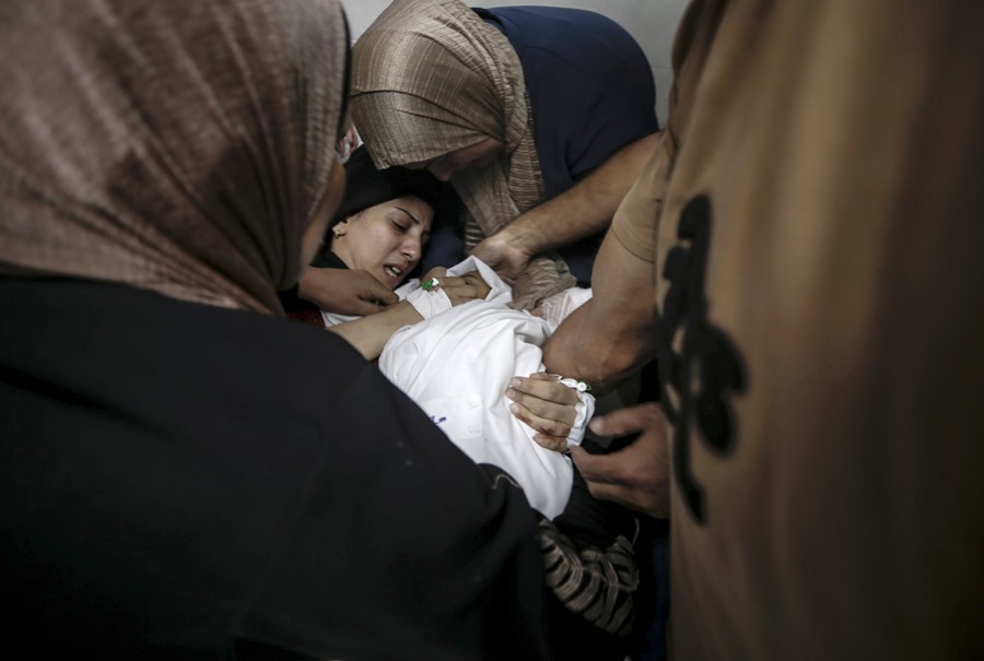 Una mujer palestina herida llora mientras sostiene el cuerpo de su hija en el hospital Al-Shifa