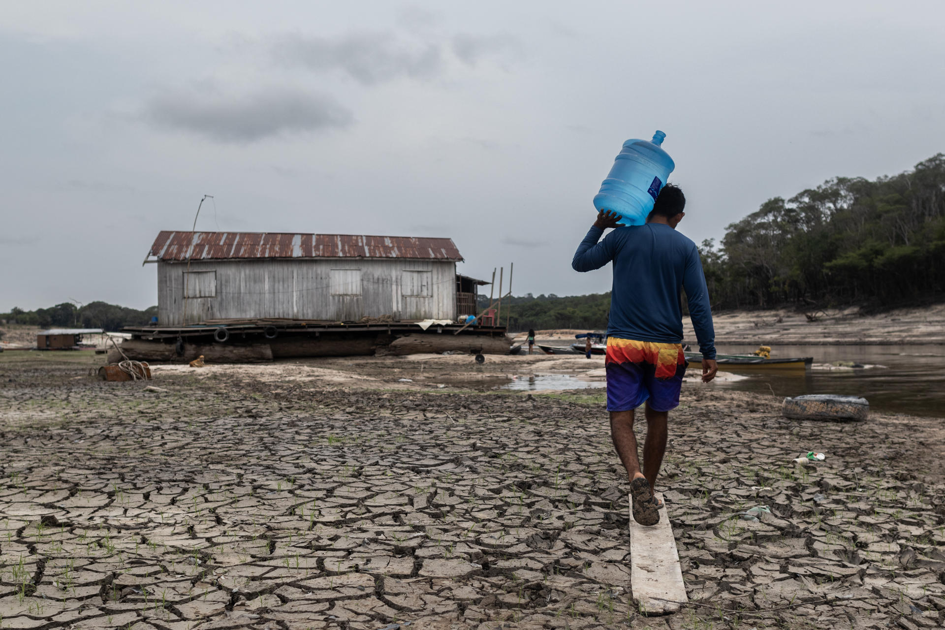 Photograph of a man carrying water to a stranded houseboat in an area known as Marina do Davi in Manaus, Amazonas, Brazil, 16 October 2023. EFE/ Raphael Alves