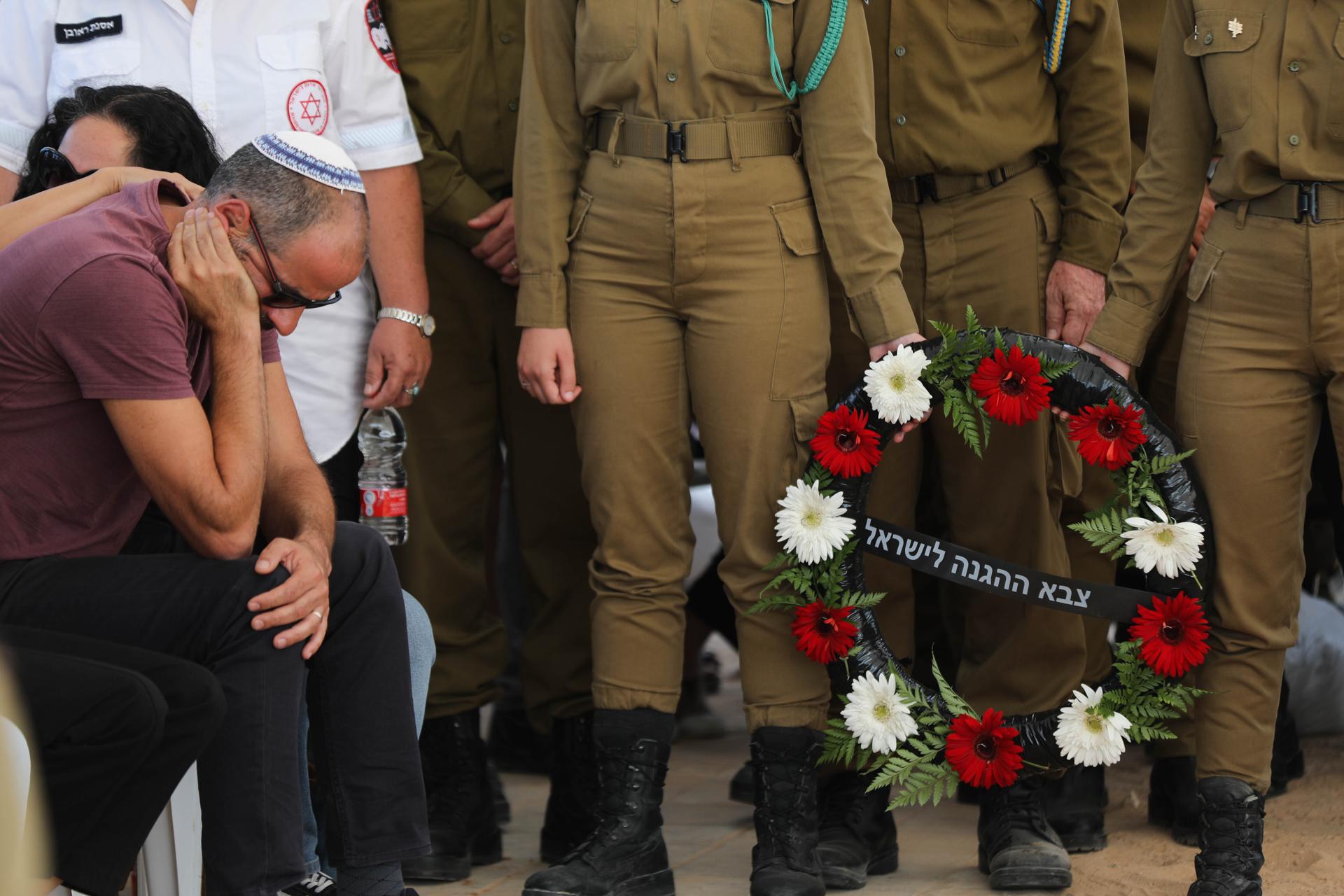 Israeli soldiers stand with a wreath as a family relative cries during the funeral of five family members of the Kutz family in Gan Yavne, Israel, 17 October 2023. EFE/EPA/ABIR SULTAN