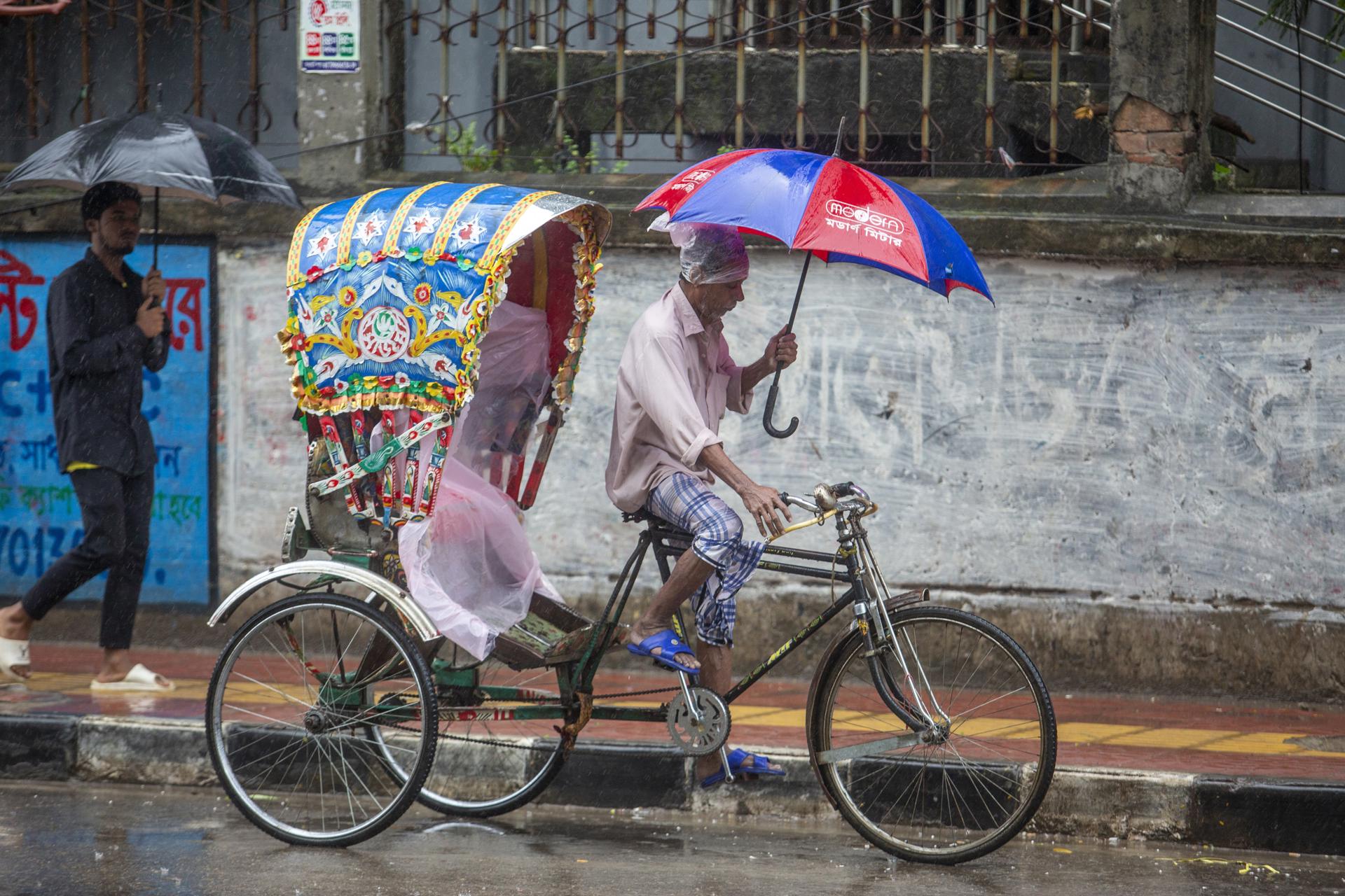 A rickshaw puller holds his umbrella during a heavy rainfall in Dhaka, Bangladesh, 24 October 2022. EFE-EPA FILE/MONIRUL ALAM