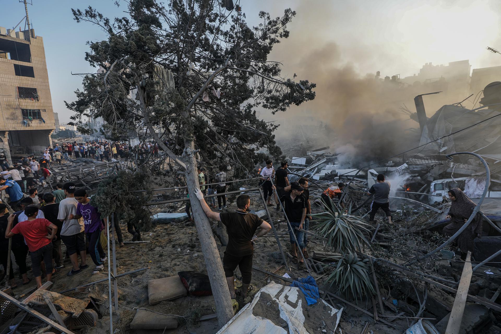 Palestinians inspect the rubble as smoke rises at a destroyed area following Israeli air strikes in Gaza City, 25 October 2023 (issued 26 october 2023). EFE-EPA/MOHAMMED SABER
