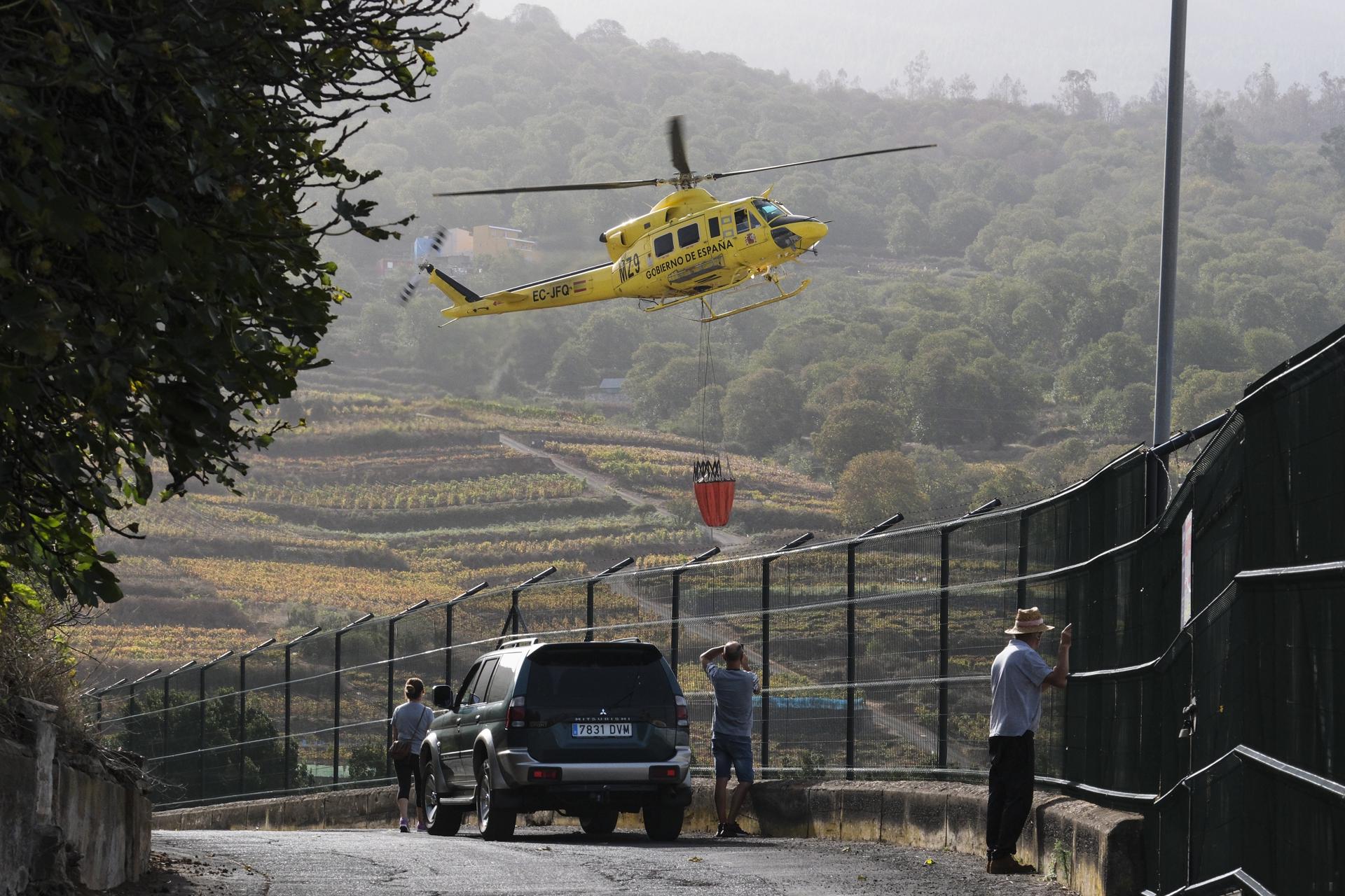 Varios vecinos de El Sauzal observan como un helicóptero que trabaja en las labores de extinción del incendio forestal de Tenerife, carga agua. EFE/Alberto Valdés