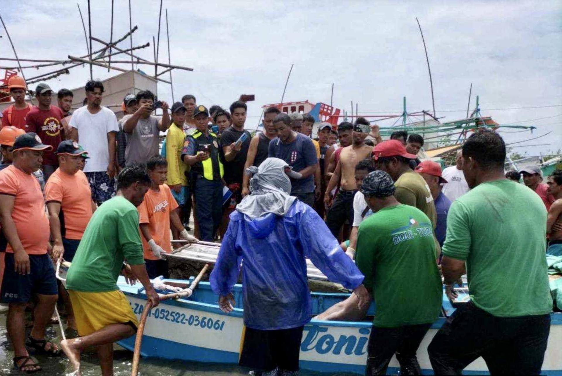 A handout picture made available by the Philippine Coast Guard (PCG) shows villagers and coast guard personnel retrieving the body of a crew member of a Filipino fishing boat in Infanta, Pangasinan province, Philippines, 03 October 2023 (issued on 04 October 2023). EFE-EPA/HO HANDOUT HANDOUT EDITORIAL USE ONLY/NO SALES