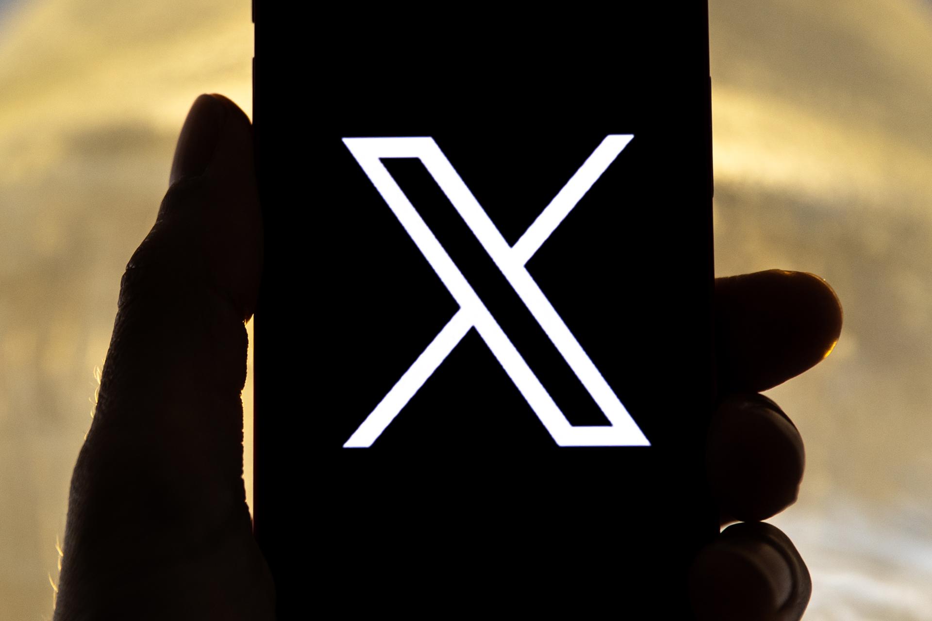 An illustration pictures shows a user holding a mobile phone displaying the 'X' logo, in Los Angeles, California, US, 27 July 2023. EFE-EPA FILE/ETIENNE LAURENT