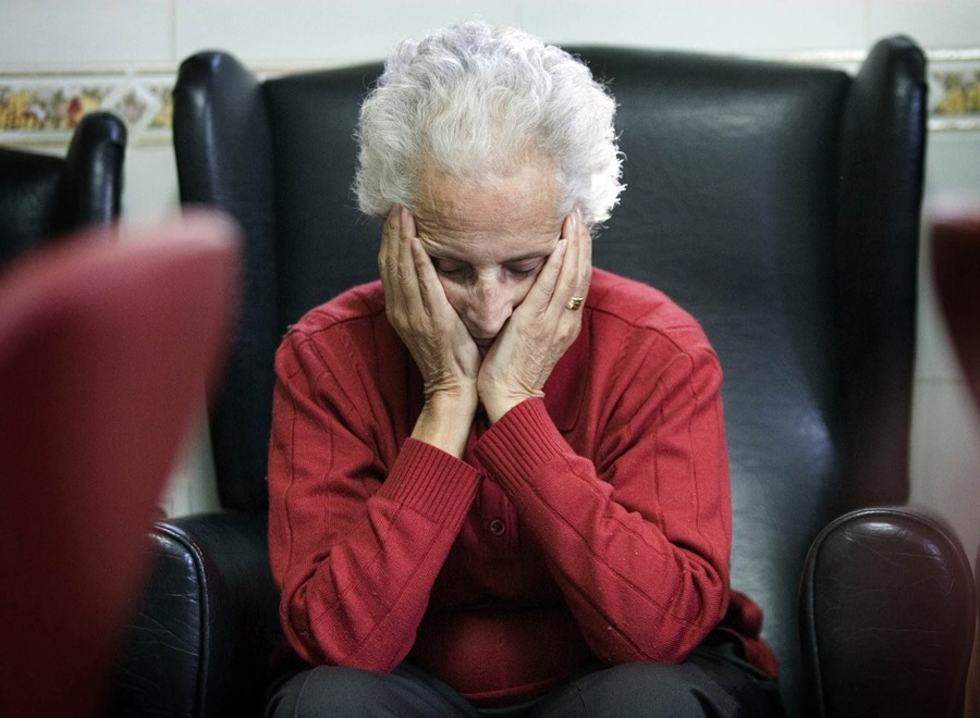 Una enferma de alzhéimer descansa en la sala de estar de un centro de día.